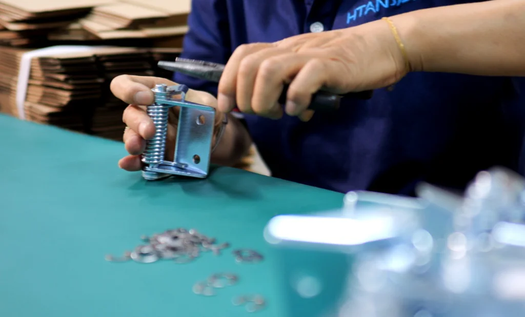Montaje manual de una bisagra industrial durante la producción OEM